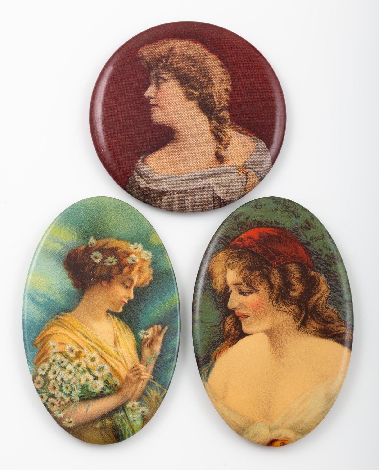 GENERIC PORTRAIT POCKET MIRRORS (3): (1) woman with scarf on head; oval; mirror slight fatigue; H-2 3/4"; (1) woman with braided hair; round; mirror has three fatigue lines; Dia.-2"; (1) oval; lovely lady with daisy hair ring and daisies