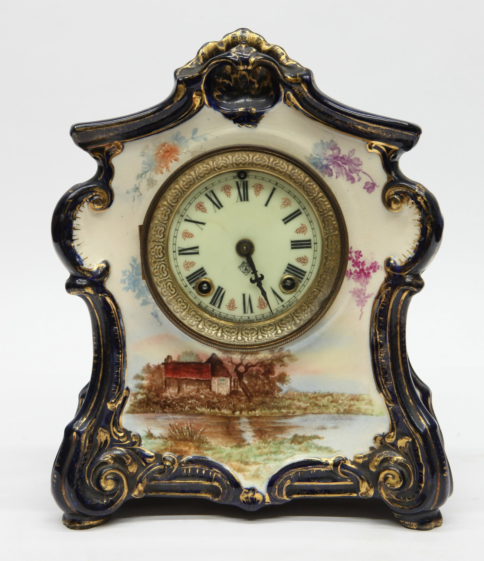 ANSONIA MANTLE CLOCK: Porcelain; Royal Bonn case; "La Blois"; cottage scene; blue and gold trim; winds; strike; dial has red inserts; some crazing; H- 11"; G-VG