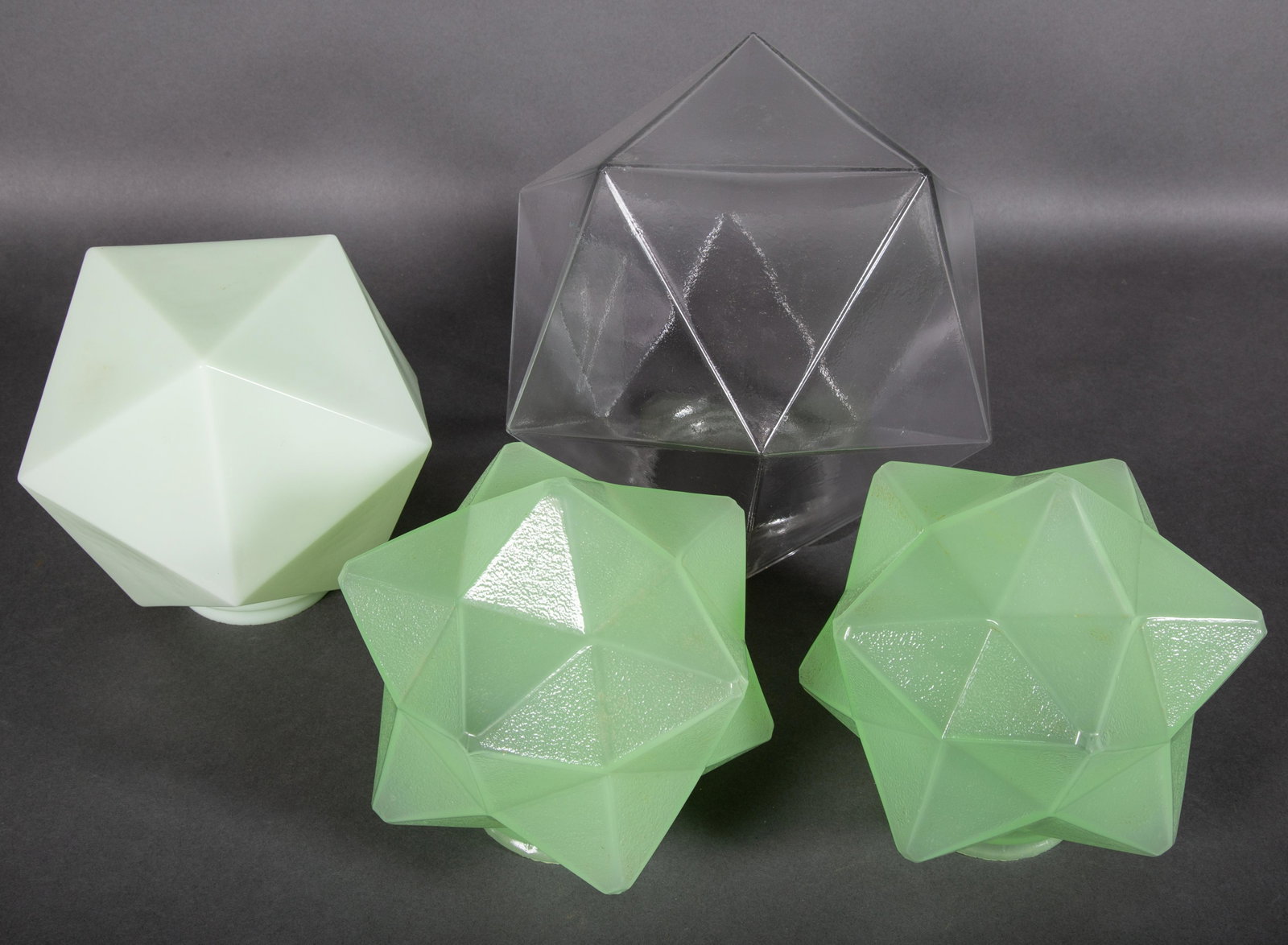 Four Art Deco Prismatic Geometric Shades for Lamps or Chandeliers: Group of four colorful Art Deco shades. A matched pair in a light olive green together with an icosahedron form apple green shade and another icosahedron form of clear colorless glass shade. Unmarked.