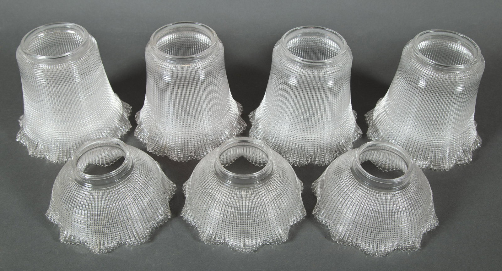 Two sets of Halophane Industrial Glass Shades: Seven Shades Total & the best Halophane shades we've seen. Please take notice that the exterior of the shades have horizontal grooves while the interiors have vertical grooves. This is what sets these