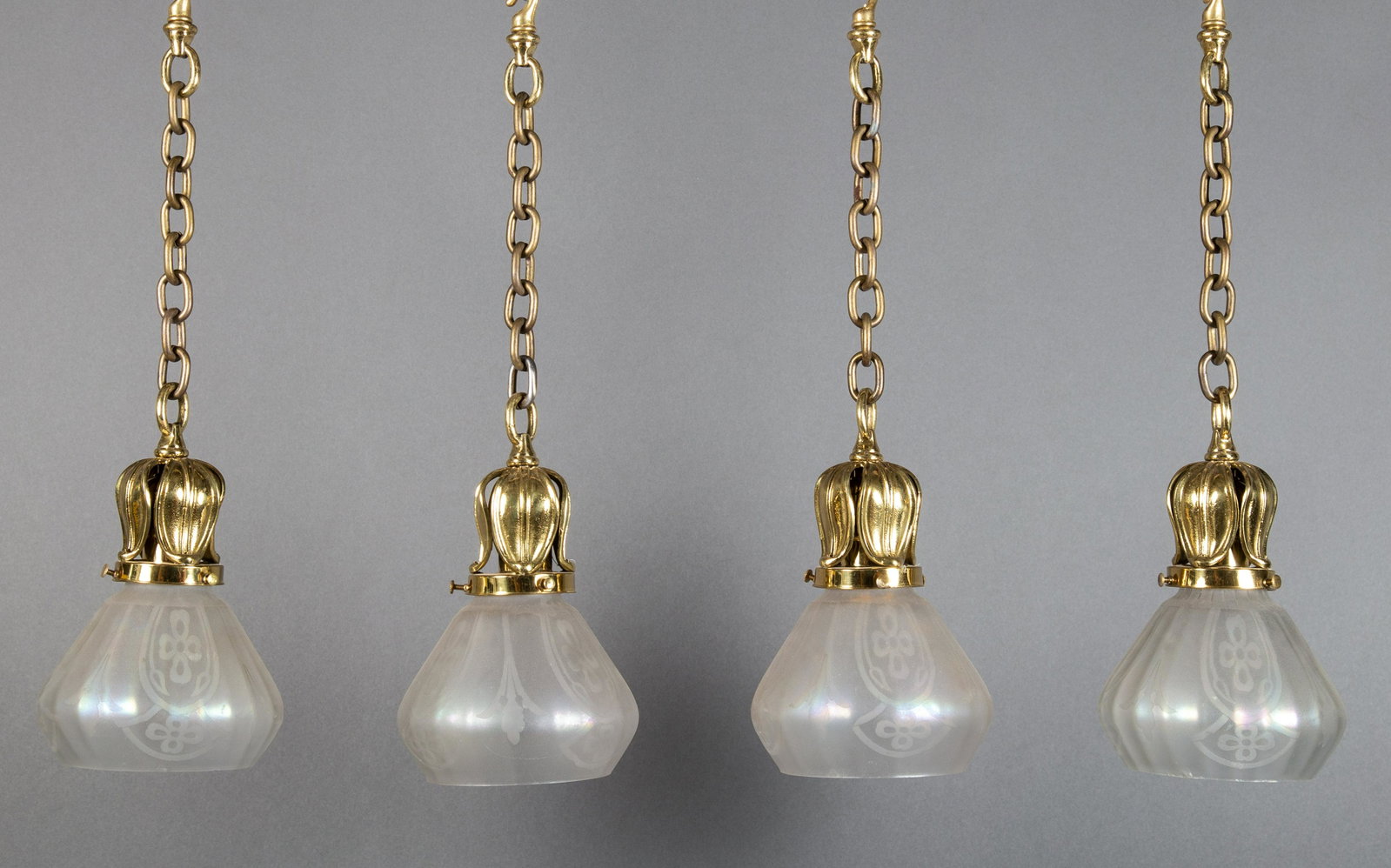Four Circa 1910 Fanciful Fitters w Art Nouveau Frosted Glass Shades: Four matching pendant lights comprised of matching frosted glass Art Nouveau shades with cast brass foliate fitters and chain. Overall height including chain is 16", 2 1/4" fitters holding 4 1/2" tall
