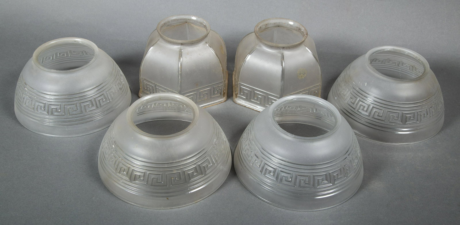 Group of Six Matching Neo-Grec Greek Key Gas Light Shades: Set of four matching, together with a pair of hexagonal shades. The set of 4 with debossed Greek key and frosted glass surfaces are 7 1/2" diameter, 3 1/2" tall with 4" fitters. The pair 6" wide from 