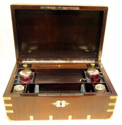 ROSEWOOD TRAVELING VANITY CASE: Rosewood with metal corners, clips, and flush handles; interior fitted with lift out tray; cranberry glass perfumes, jars, bottles and glasses; some minor case restoration; (1) cup chipped; may or may