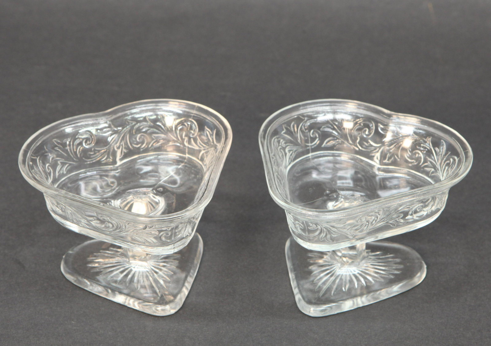 HEART ICE CREAM DISHES (2): Marked "J. M. Pat Pending" clear pressed glass heart shape with foliate designs, normal wear, H-3 1/4", Dia.-4 1/2", VG-EX