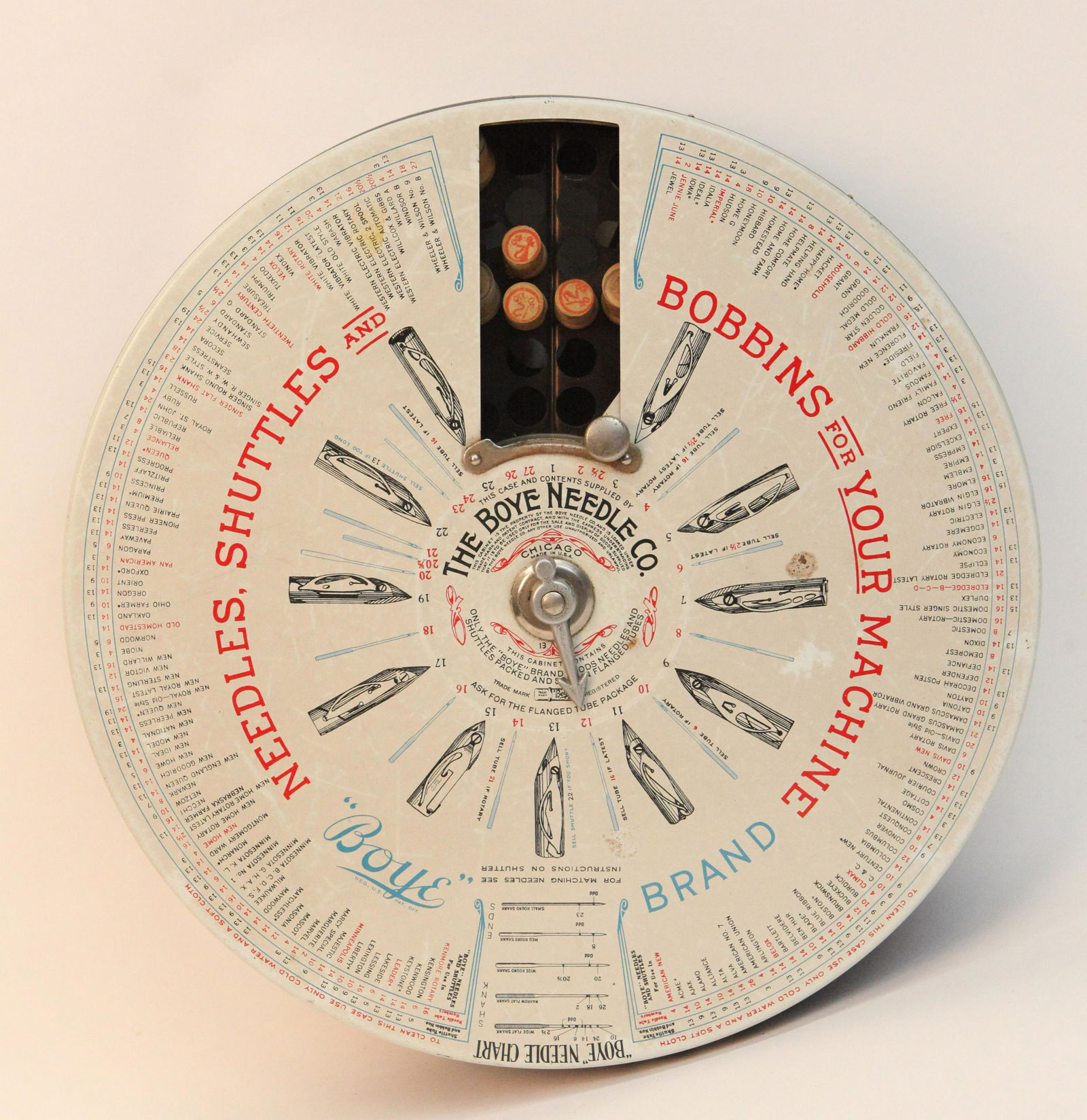 "BOYE" NEEDLE CASE: Tin litho, interior spins to desired pictured item; interior has wood cylindrical containers with product; normal wear; VG-EX