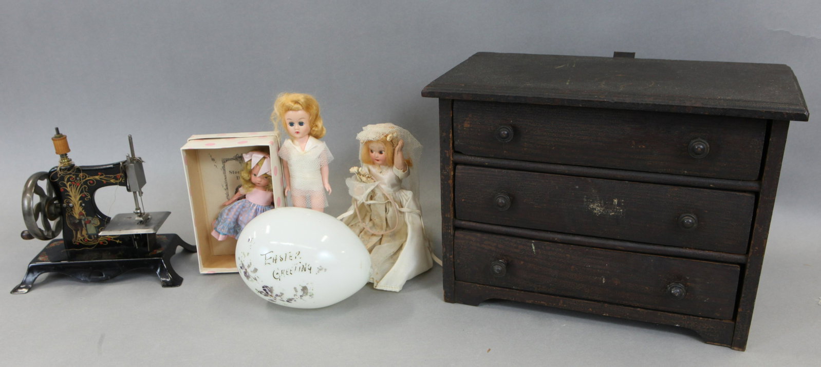 DOLLS & RELATED: (1) Child's sewing machine, Germany, metal, Little Red Riding Hood stencil; (1) milk glass Easter egg, (4) small composition dolls, storybook, etc., 1-needs re-stringing; (1) oak doll dresser, normal 