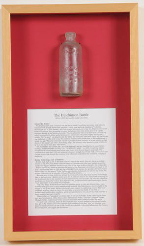 EARLY BIEDENHARN CANDY COMPANY HUTCHINSON BOTTLE: 26" x 15" total frame measurement; this is an actual bottle, nicely displayed in showcase frame mounting used in the museum, with detailed explanation of the story and use of the Hutchinson bottles; s