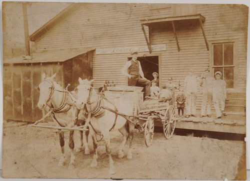 CIRCA 1910 COCA-COLA PHOTOGRAPH: 6" x 8"; great photograph features man standing in horse drawn Coca-Cola bottling works early wagon with kids holding straight-sided bottles and banner on building; probably an early bottling plant; 3