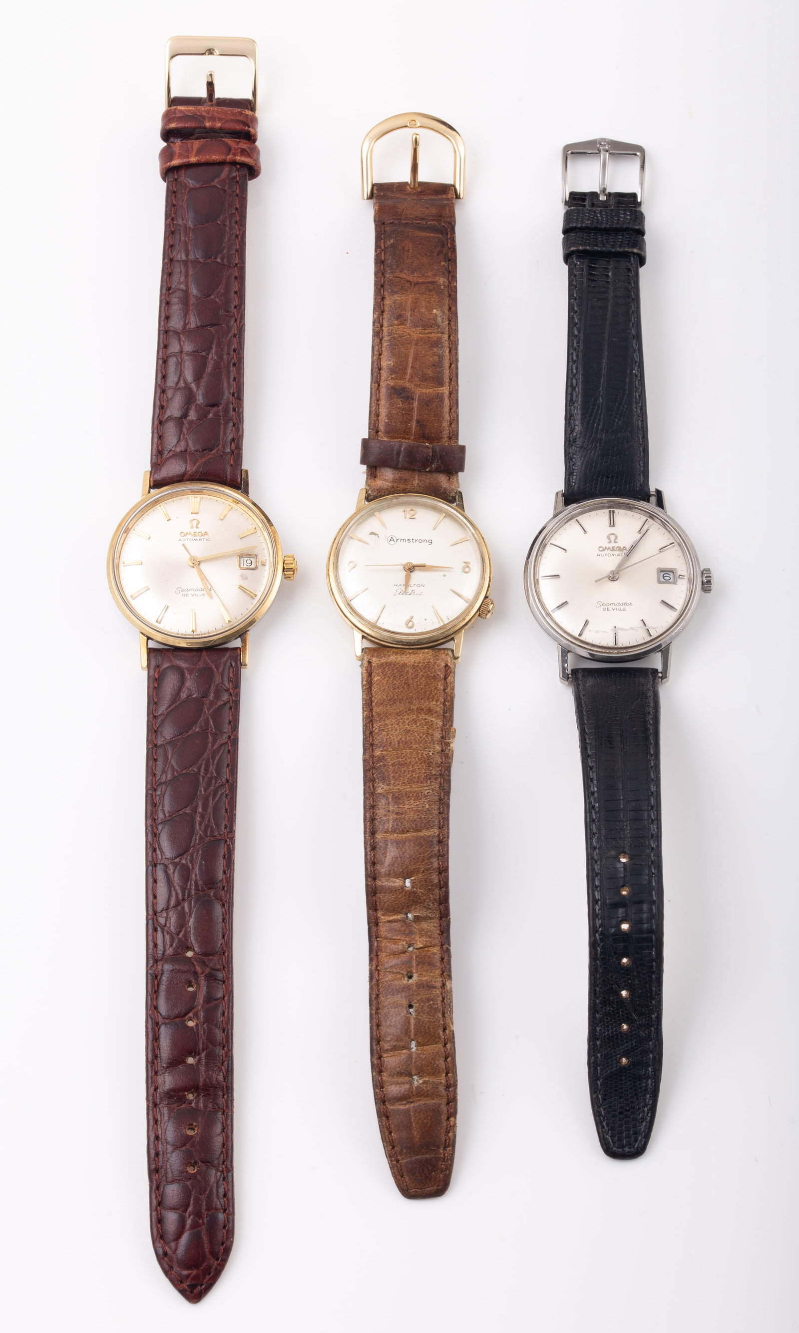 (3) PCS. OMEGA & ARMSTRONG MEN'S WATCHES: (2) Omega: 1-gold tone with brown leather band, University of Baltimore; 1-silver tone with black leather band; (1) Armstrong, 10K gold with brown leather band; 2-running; average wear; L-8"-10", G-VG