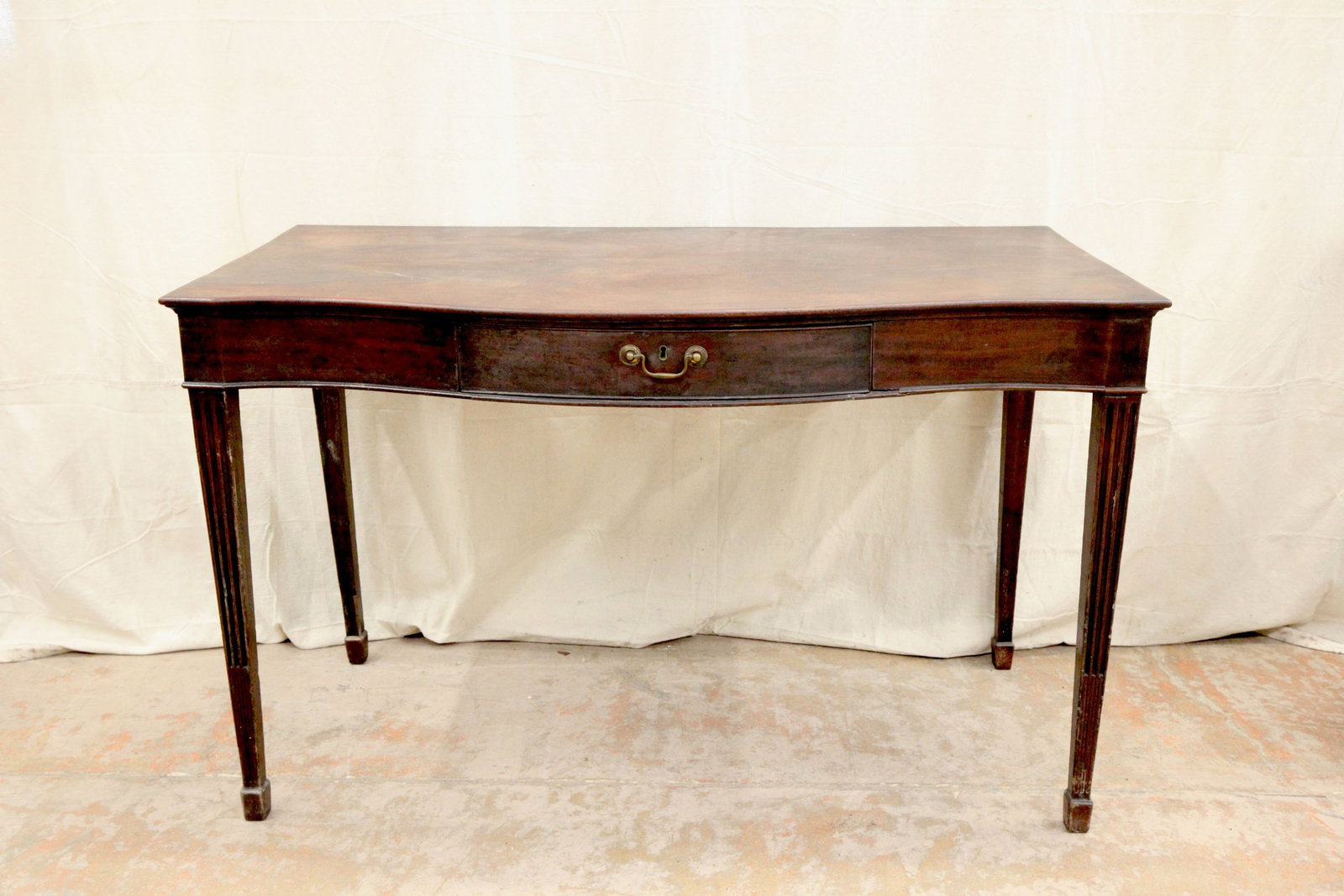 GEORGE III HUNTBOARD / SERVING TABLE: Serpentine top of Santo Domingo mahogany; center silver drawer; square tapered reeded leg; top checking and wear; H-35", L-56", F-G