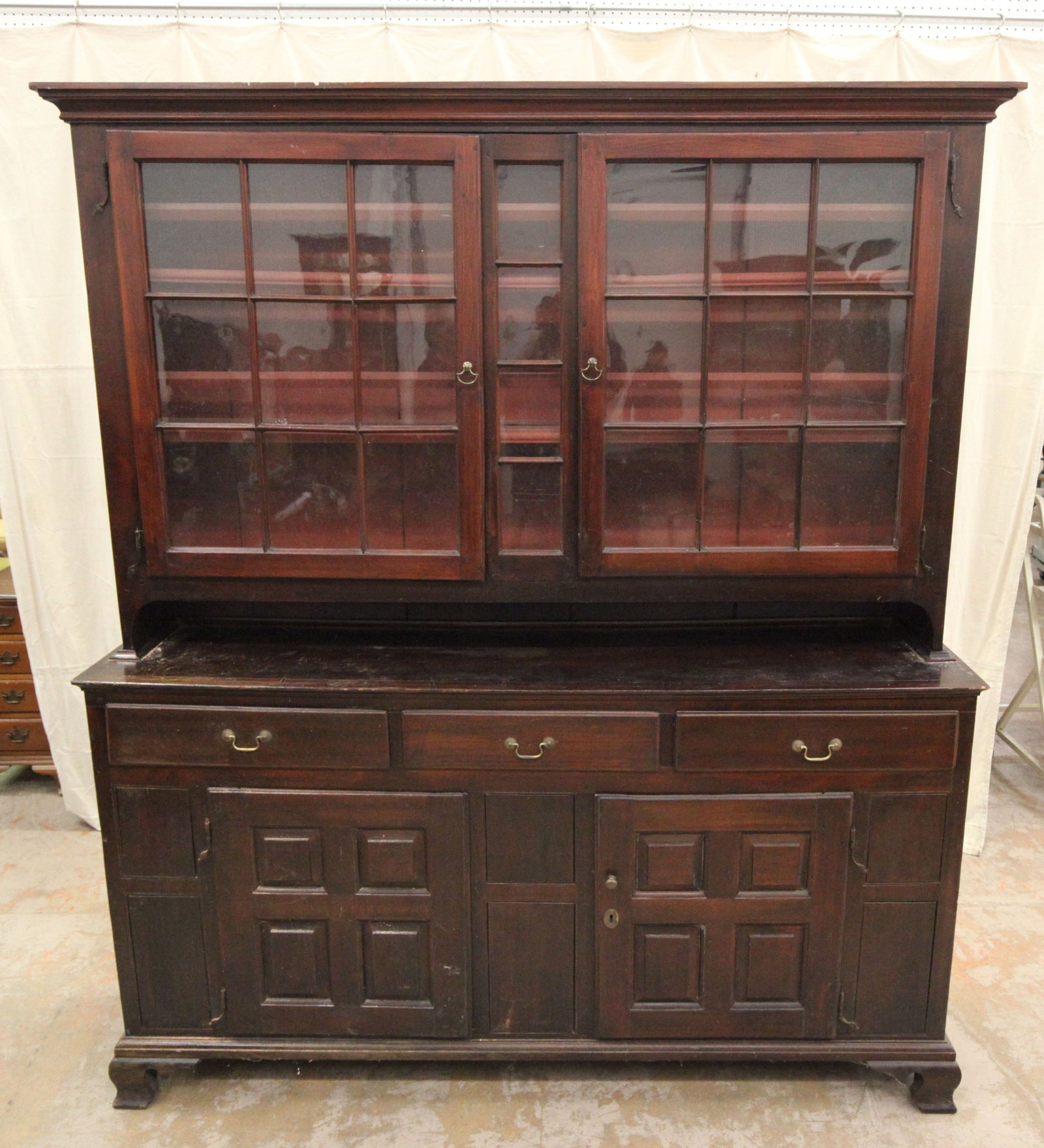 CHIPPENDALE DUTCH CUPBOARD: Two piece; mixed wood with dark stain; top has two mullioned doors; rat tail hinges; three drawers over two raised panel doors; ogee bracket feet; wear; H-95", L-73", G-VG