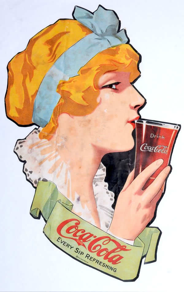 CIRCA 1916 COCA-COLA PAPER CUT-OUT SIGN: 14" x 9". Strong color remains with a few small closed tears, some stronger bends, some minor color chips and nicks with light repair from behind. Medium to darker mildew spots and stains. Still displ