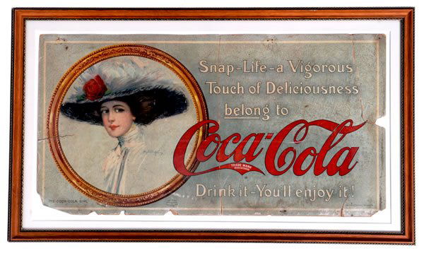 1910 COCA-COLA CARDBOARD TROLLEY SIGN: Framed under glass, and measures 11" x 21". This piece is all original and presented in as-found condition. A number of closed tears, general surface wear, minor soiling, edge chips and nicks and a fe