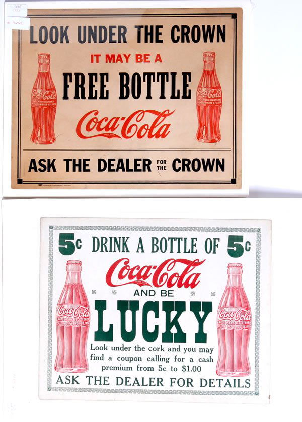 2 COCA-COLA CARDBOARD SIGNS: Both measure 11" x 14". "Lucky" is circa 1923 and "Free Bottle" is circa 1935. Nice pair of signs with related themes. The 1923 sign is bordered by the old Indian good luck symbol, or swastikas, and t