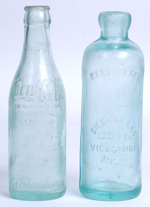 BIEDENHARN BOTTLES – HUTCHINSON AND STRAIGHT SIDED: The hutch bottle is only lightly clouded or worn with a slight caved or slumped right side. The straight bottle has medium surface scratches and wear. Condition 7.5 to 8.5 / VG-EX