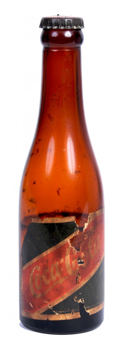 COCA-COLA LATE 20S PAPER LABEL EXPORT BOTTLE: Wear, soiling, and chipping on the label and is missing the neck label. Cap appears to be original with some surface rust and still has about 2.5 oz. in the bottle. Seems not to have been opened. The 