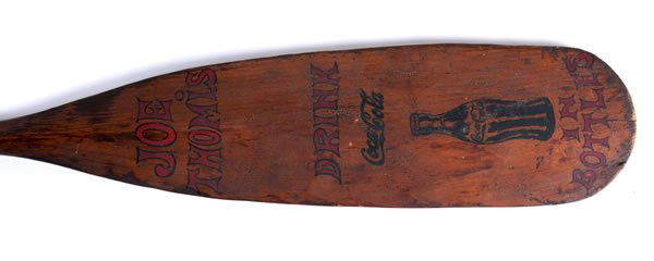 FOLKY COCA-COLA CANOE PADDLE: 67" x 7". Entitled and paint decorated design on both sides. One side reads "Chief Paduke", the other side reads "Joe Thomis, Drink Coca-Cola in bottles" and shows a hobble skirt bottle. Vintage is ci