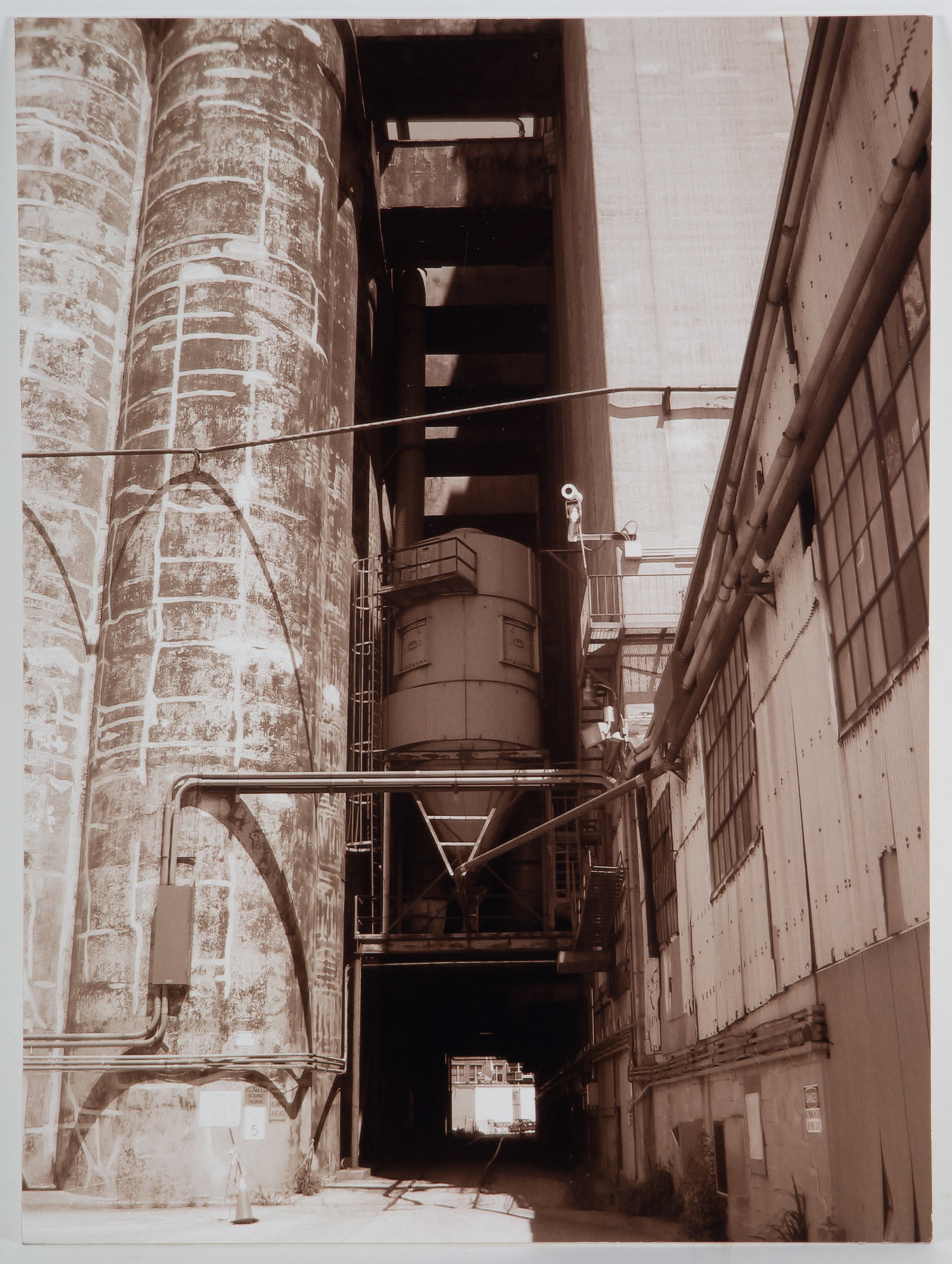 LOCUST POINT INDUSTRIAL PHOTOGRAPH – JEANINE TURNER: Jeanine Turner, (20th Century), “In the Middle: Locust Point Grain Elevator”, 2004, Sepia tone Photograph mounted on Board, Image Size: 20” x 15