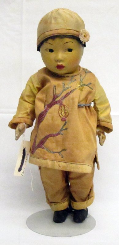 ORIENTAL BOY DOLL: Composition; original clothing; paint blemishes on left side of face; some paint flaking on back and hands; 1" tear on shirt and wear spots; H-14", G