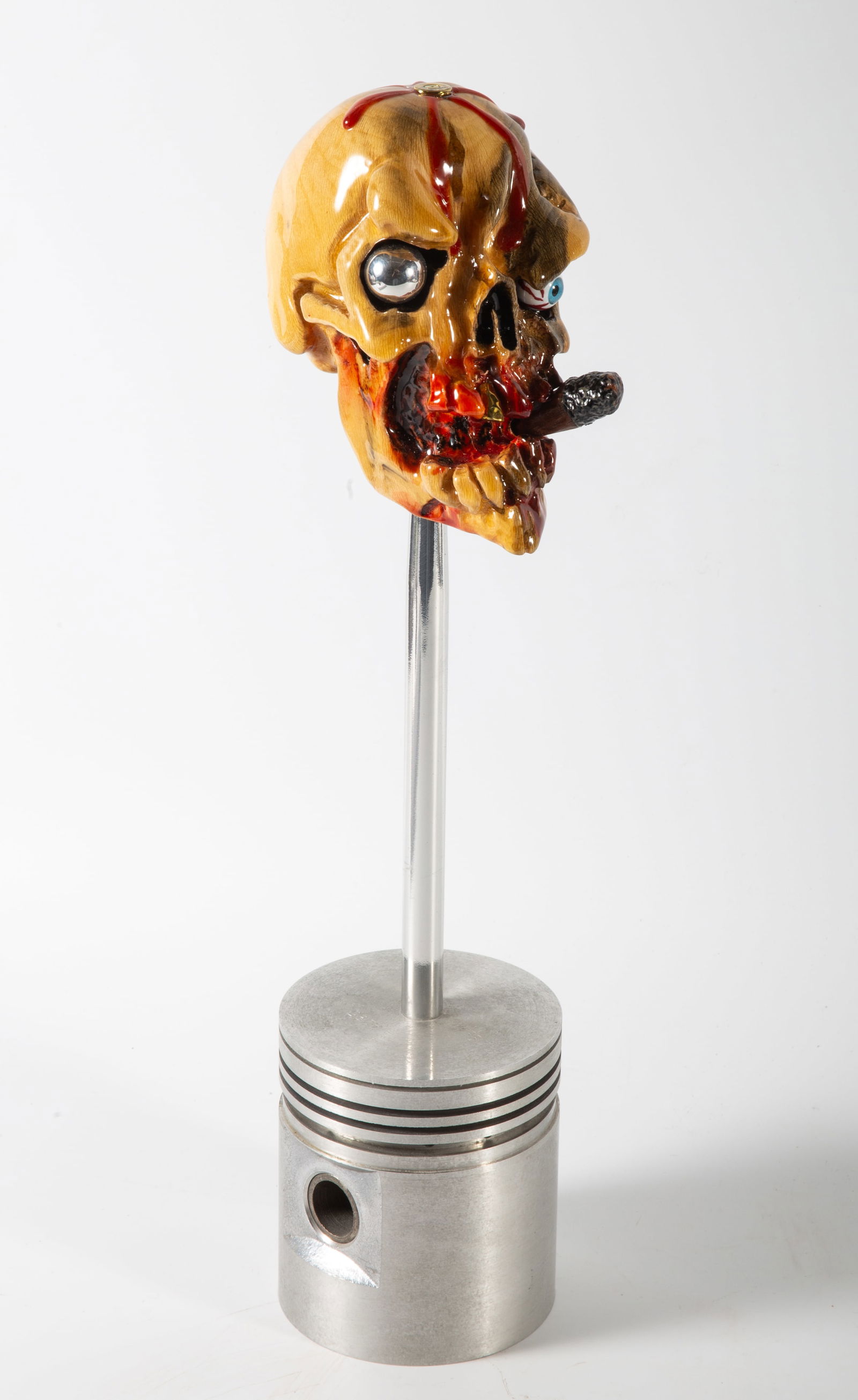 N. GRABOWSKI SHIFTER HEAD: Custom made shifter head, signature button; various materials; this scary guy has a ball bearing eye, a gold colored tooth and smokes a cigar; mounted on a piston; comes with two autographed posters;