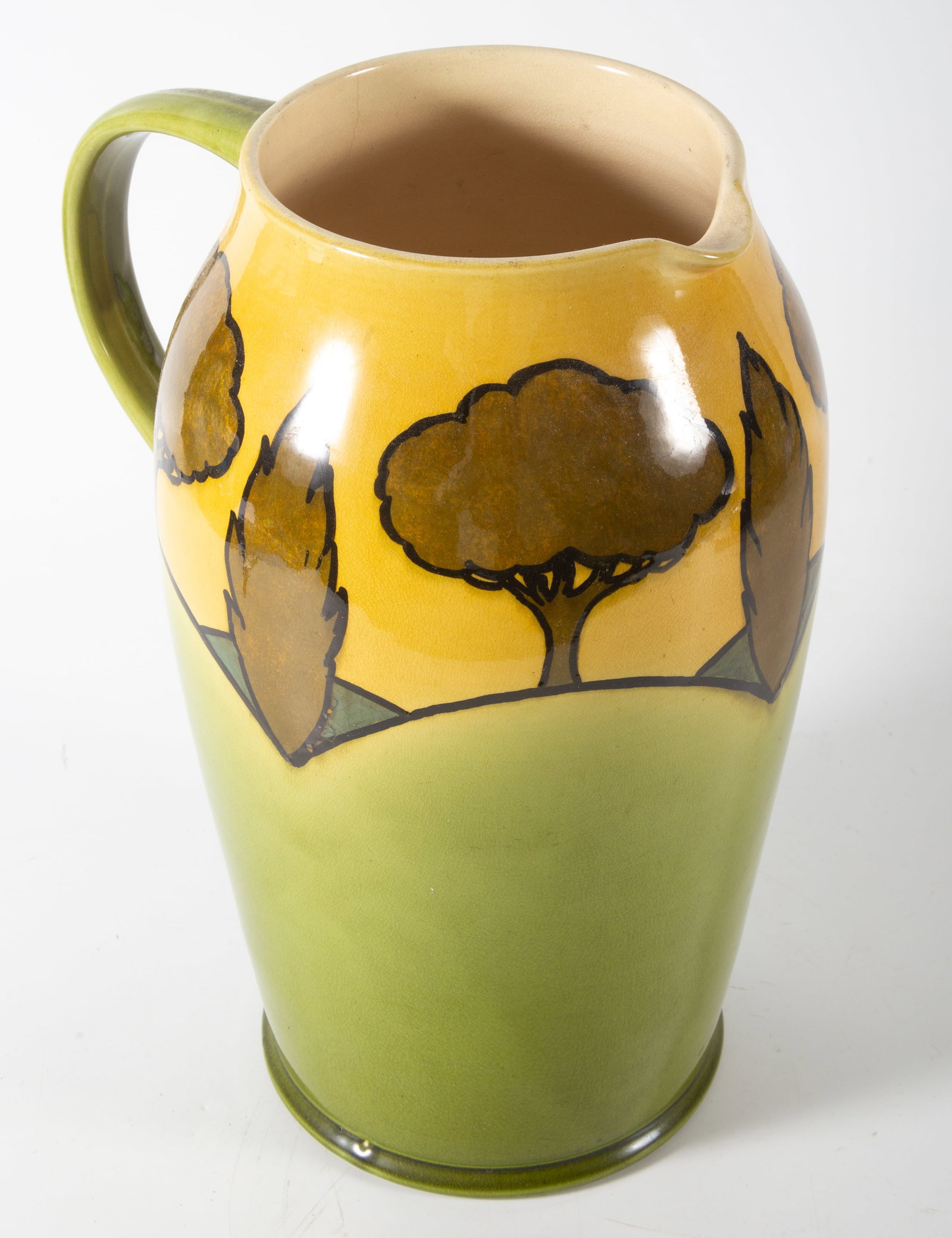 ARTS AND CRAFTS CERAMIC PITCHER: Green and yellow glaze; tree and foliage pattern; H-12 1/2"; normal wear, VG