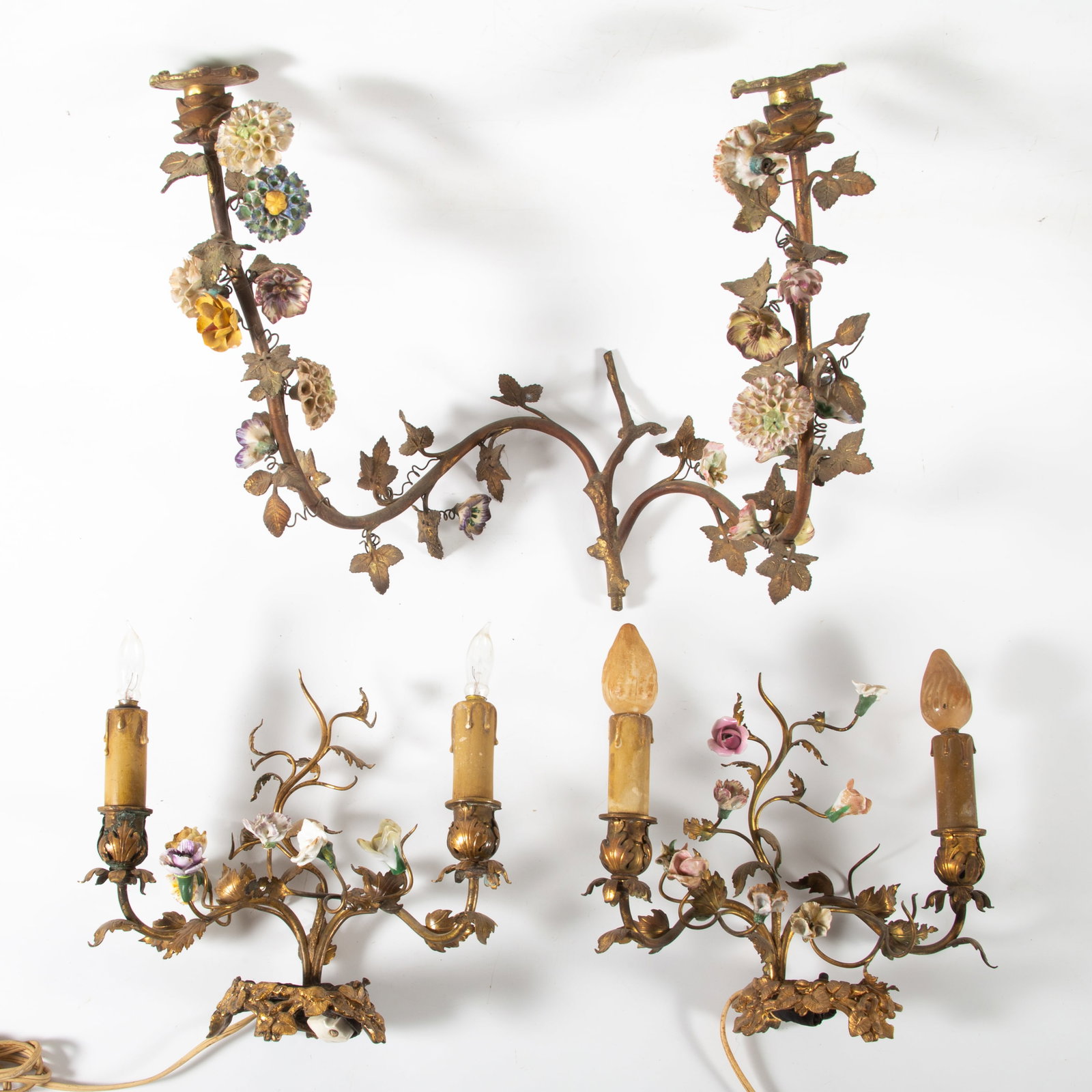 DECORATIVE FLORAL SCONCES: Gilt metal and applied porcelain flowers; (1) large candle sconce- two arms with candle cups, H-13"xW-14"; (1) pair of gilt metal table lights- electrified, both missing a central object,