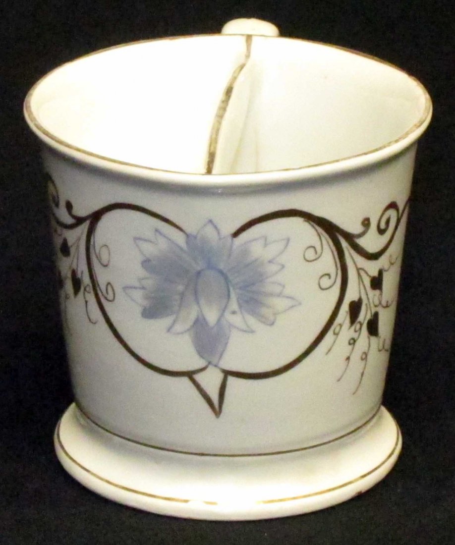 MUSTACHE CUP: Painted porcelain, blue flower and gilt decoration; minor gilt paint loss on top edges; small area of discoloration at base; H-3 1/2", G-VG
