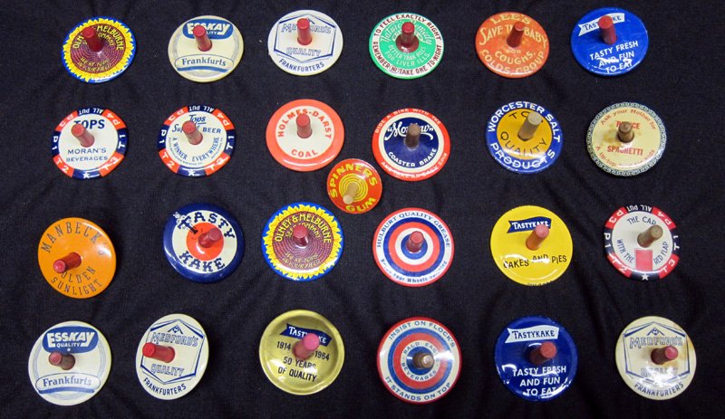 ADVERTISING TWIRL TOPS (25): Mostly food products: Esskay, TastyKake, Natures Remedy, beer, etc.; tin, celluloid; some with stains; Dia.-1 1/2", G-VG