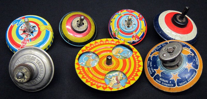 TIN TOPS (8): Tin litho; mostly launcher type, (2) launchers; (1) fortune telling; movie top is twirler; (1) Hy Speed Top: litho tin with sailboats, original box; Dia.-3" - 4 1/2", G-VG