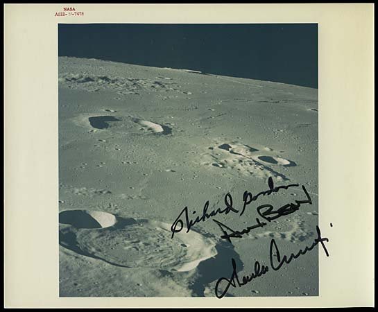 1969 APOLLO 12 CREW SIGNED PHOTO OF MOON: Original NASA issued 8"x10" color press photograph (with red serial ID numbers) that shows a nice close-up view of the Moon surface as seen from Apollo 12. Photo boldly signed in black sharpie by Astr