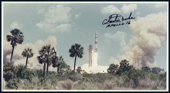 1972 CHARLIE DUKE SIGNED PHOTO: A 14x11" Apollo 16 launch photo signed by Charlie Duke in black sharpie. The photo is glued onto 20"x16" white matte. In overall good condition, matte shows toning and worn corners.