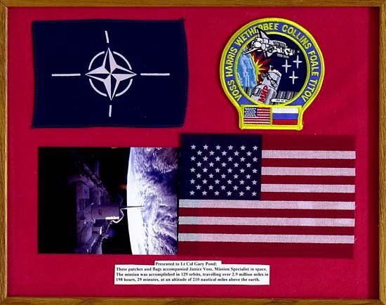 1995 STS-063 FLOWN FLAG & PATCHES: Glass protected framed display, overall size 16¼"x13¼", containing pennant, USA flag and crew patch, all flown. Also has color photo from mission. Printed description indicates that display was pres
