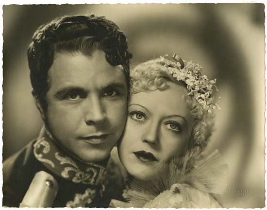 MARION DAVIES & DICK POWELL PHOTO BY MANATT: A 10x13" borderless gelatin silver matte double-weight, deckled-edged photograph of Marion Davies and Dick Powell in a promotional shot for the film "Hearts Divided". Oversized photo taken by James Ma