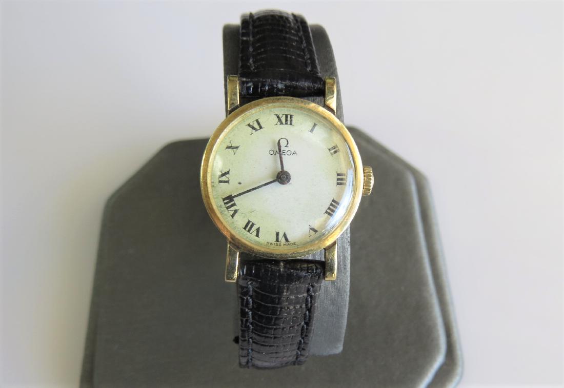 14K Yellow Gold Vintage Omega Watch: Womens vintage 14K yellow gold Omega wrist watch with black genuine leather band by Hadley-Roma. Swiss made. 16mm case. Ivory face. 8mm band width with 7 adjustable wrist sizes. Roman numeral time mar
