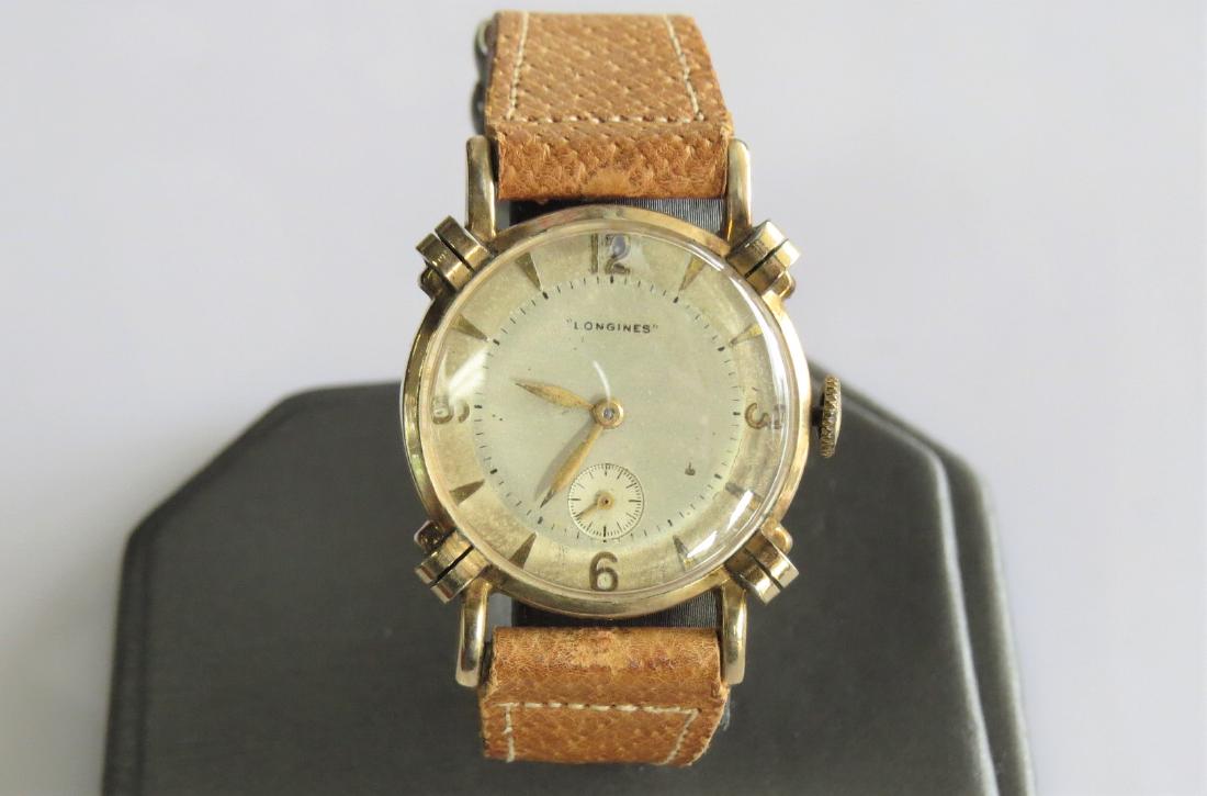 Vintage 10K Yellow Gold Longines Watch: Vintage mens 10K yellow rolled gold case Longines wrist watch. Swiss made. 15 jewels. Tan genuine pigskin band. 26mm case - 15mm band width with 6 adjustable wrist sizes. This watch was manufactured i