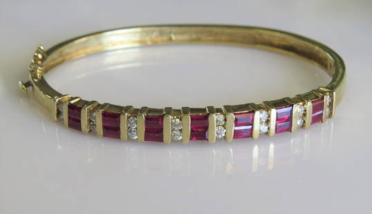 14K Yellow Gold Ruby and Diamond Hinged Bangle Bracelet: 14k yellow gold ladies hinged bangle bracelet set with approximately .50cttw round diamonds and approximately 2.00cttw emerald cut rubies. Weighs 15.6dwt. about 2.5" diameter.