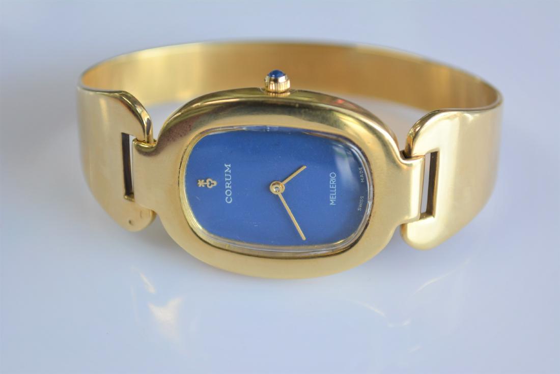 Corum Mellerio 18K Gold Watch: Beautiful 18 karat yellow gold Corum Mellerio 1780M bangle style ladies watch. Hook latch closure. Serial number 57300. 1- oval case. Royal blue face. 47 DWT/73.1 Grams.