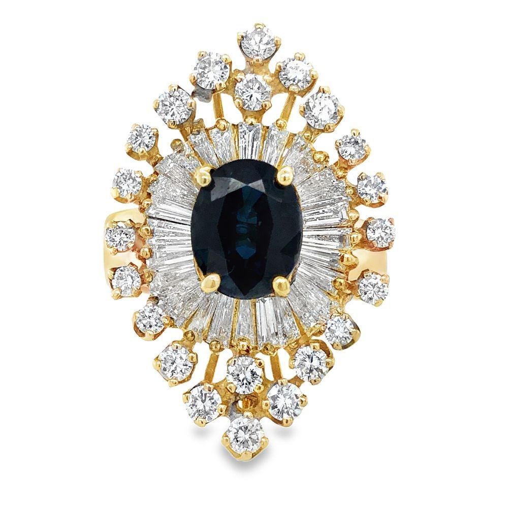 Diamond Accented Sapphire Statement Ring: S/10.0-OKSS A truly magnificent and eye-catching cocktail ring featuring a prominent oval-cut natural blue sapphire at its heart, radiating a deep, luxurious color. This central gem is dramatically