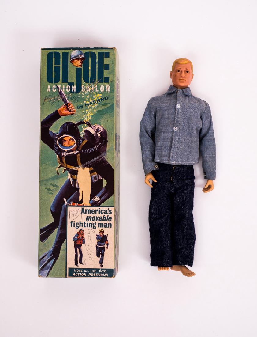 1964 G.I. Joe Action Sailor OB: DESCRIPTION: 1964 G.I. Joe Action Sailor item # 7600 (blonde) in original coffin box. CONDITION: Missing hat, dog tag, boots, pamphlet, insignia, and manual. Stress crack to right knee. Writing to lid