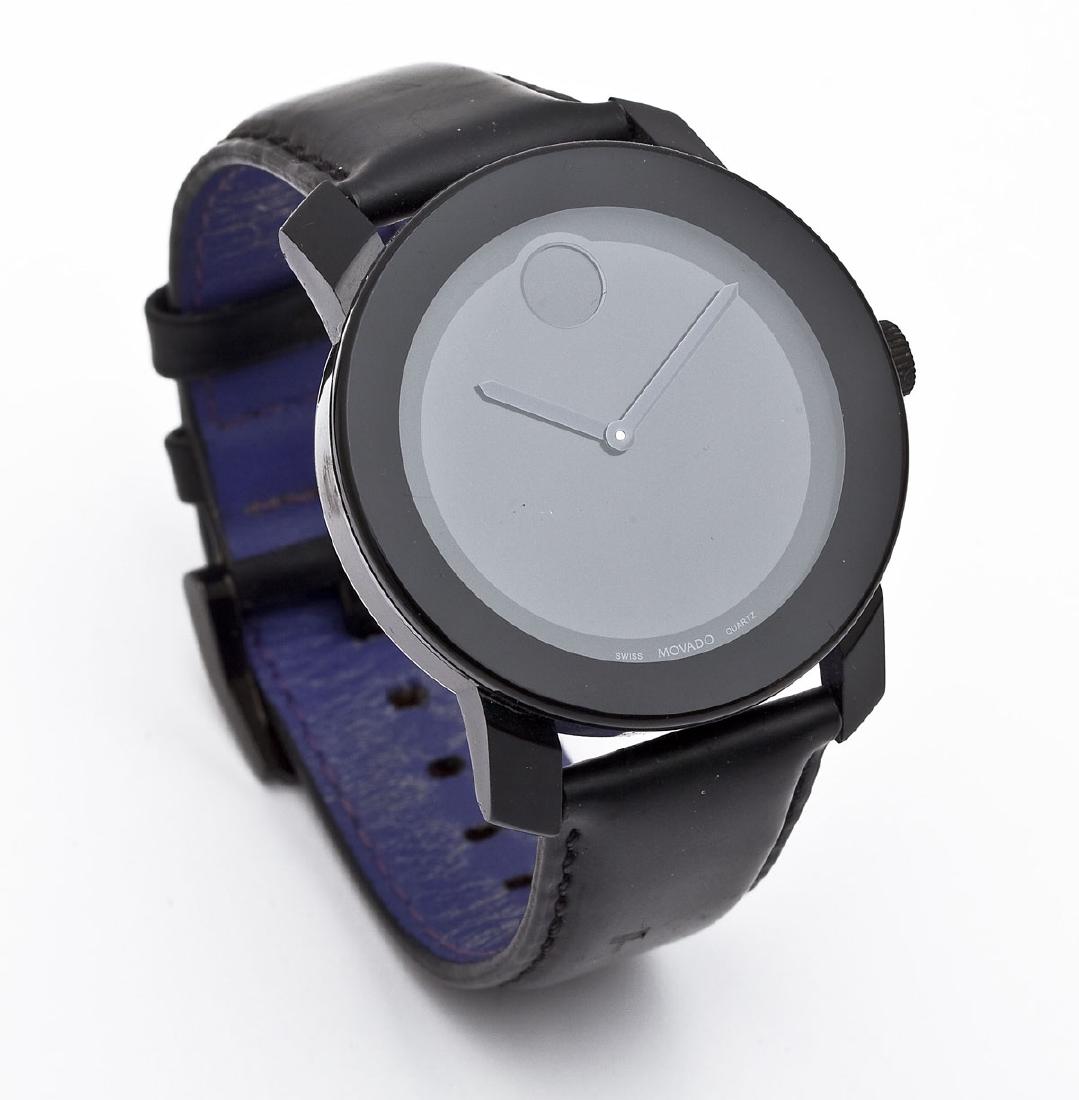 Movado Bold Quartz Wristwatch in OB: DESCRIPTION: Movado Bold quart wristwatch. All black dial, case and band. Back of case marked "Movado Bold 10821658 Stainless Steel Water Resistant MB.01.129.6003". With Movado Bold band. In original