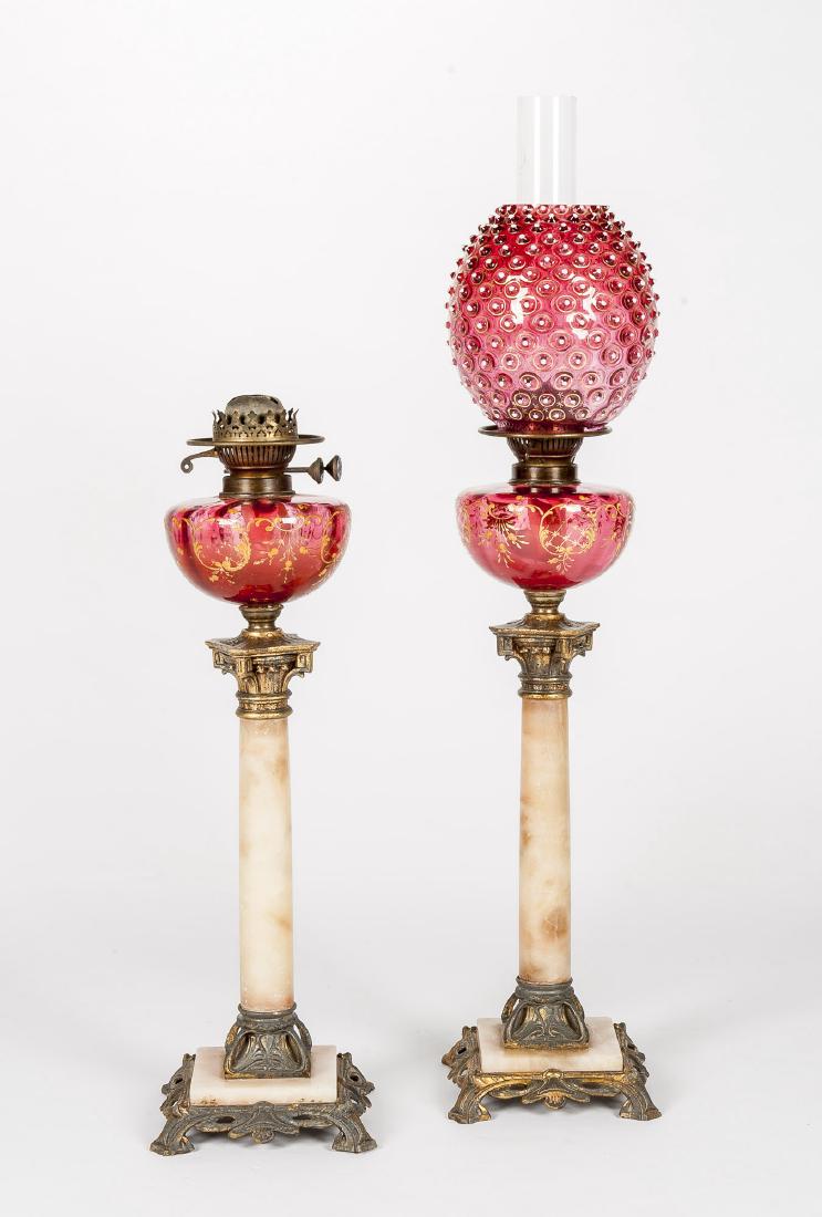 Pair of Cranberry Glass and Onyx Oil Lamps: DESCRIPTION: Pair of cranberry glass and onyx oil banquet lamps. Enameled floral decorated cranberry glass font upon onyx and gilt spelter base. Twin burners. One with gilt and enameled embellished cr