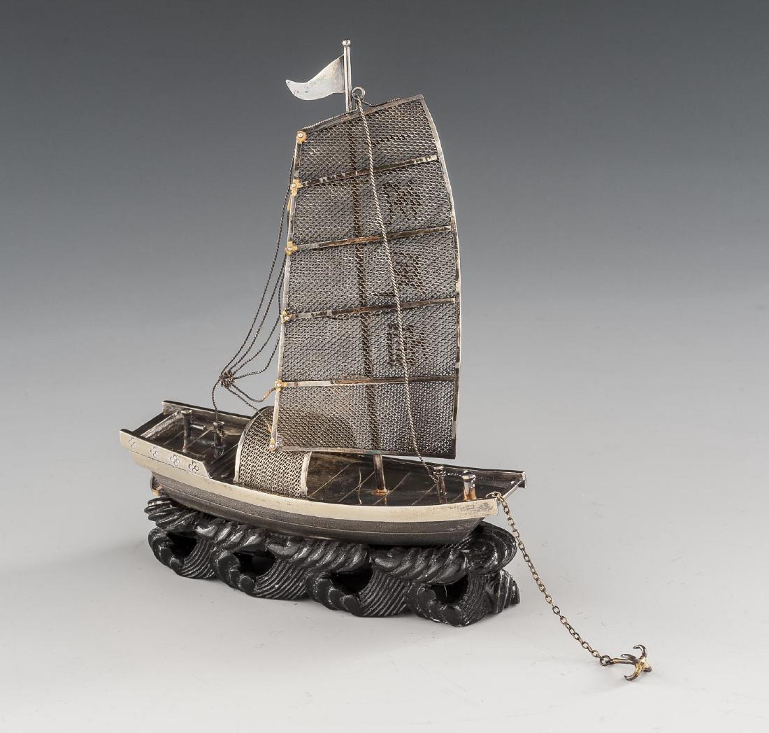 Silver Junk on Carved Wood Base: DESCRIPTION: Silver junk attached to carved wood base. Single sail ship with four Asian characters applied to sail. Lines and anchor attached by chain intact. Marked "Silver" by rudder. MEASUREMENTS: