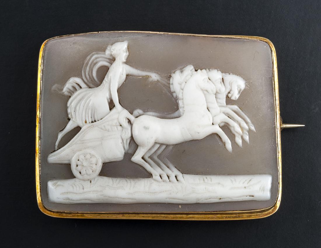 Victorian 14K Chariot Cameo Brooch: DESCRIPTION: Carved cameo depicting classical figure with horses and chariot, in 14k (tested) frame. Carved "W" to back of cameo. MEASUREMENTS: 1-1/2" x 2". CONDITION: Light wear.