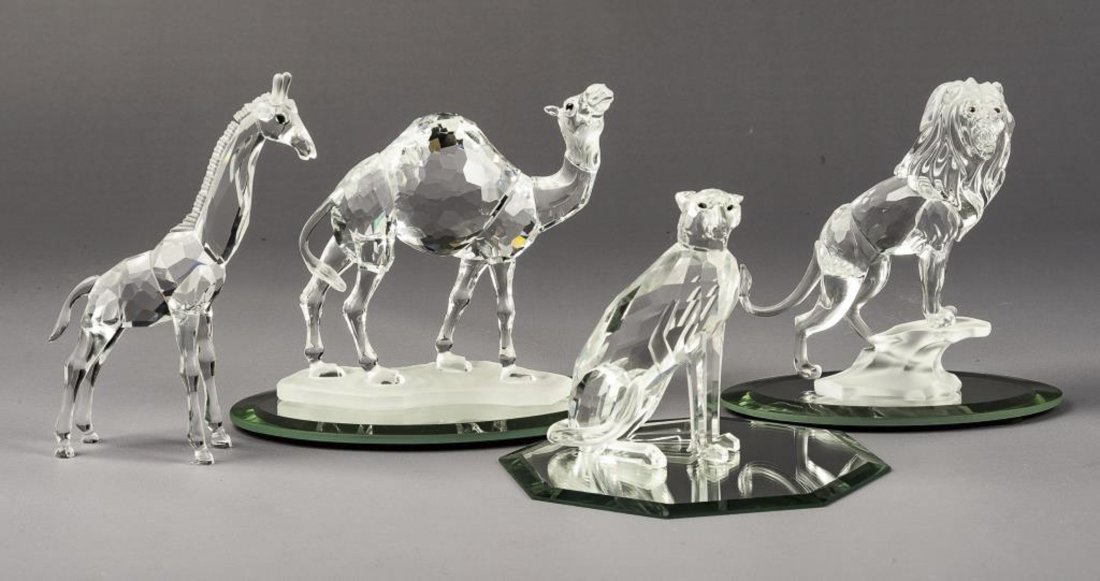 4 Swarovski African Wildlife Animals: DESCRIPTION: Four Swarovksi Wildlife Africa Series animals with three mirrored bases. Includes 247683 Camel, 269377 Lion, 236717 Baby Giraffe, and 183225 Cheetah. MEASUREMENTS: Various. Ranges from 2-
