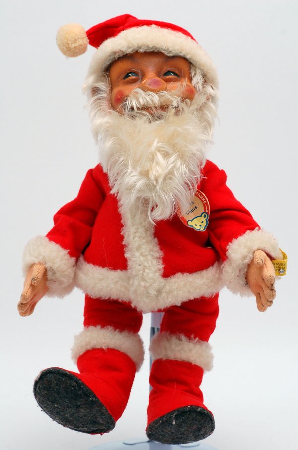 C 1953 Steiff Santa Claus: DESCRIPTION: Circa 1953 Steiff Santa with painted composition face and red felt suit with lambs wool trim, with original tags. MEASUREMENTS: 12-3/8". CONDITION: Light crazing to face.