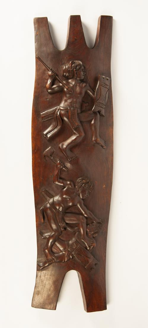Decorative War Shield: DESCRIPTION: Decorative war shield. In the style of Igorot tribe headhunter shields from the Philippines. Carved fighting figures to front. Recessed hand hold center back. MEASUREMENTS: 12-3/4" x 46-1