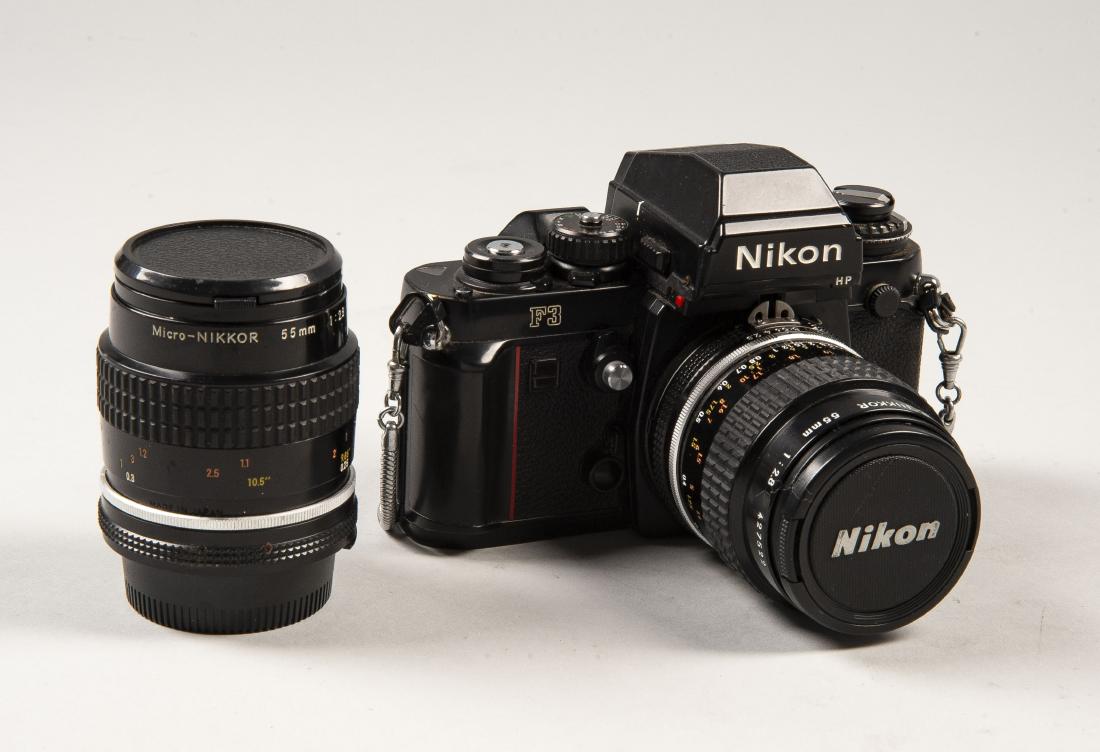 Nikon F3 HP with 2 Lens: DESCRIPTION: Nikon F3 HP with two Micro-Nikkor 55mm 1:2.8 lens. Serial number 1676858. Includes silver chain strap and original gold "Passed" quality assurance sticker. MEASURMENTS: Various. CONDITION