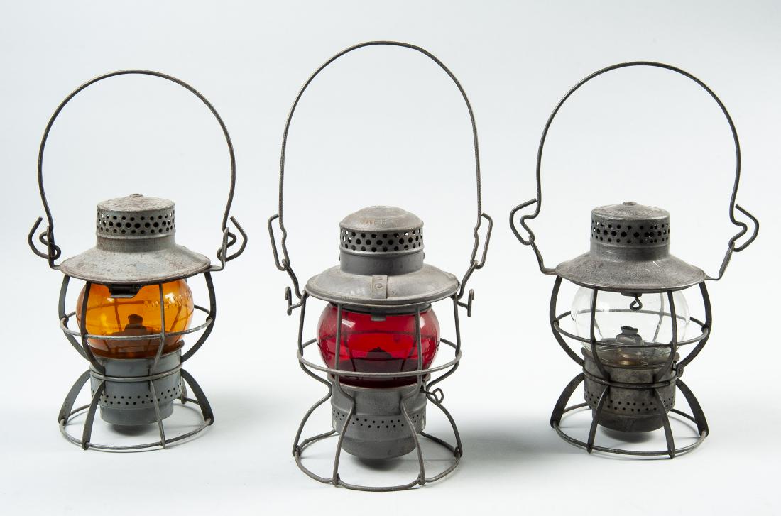3 Railroad Lanterns: DESCRIPTION: Three railroad lanterns. Includes: 1) Clear globe PRR lantern. With Dressel Arlington, N.J. embossed on top. 2) Amber globe Northern Pacific lantern. With Dressel Arlington, N.J. embossed