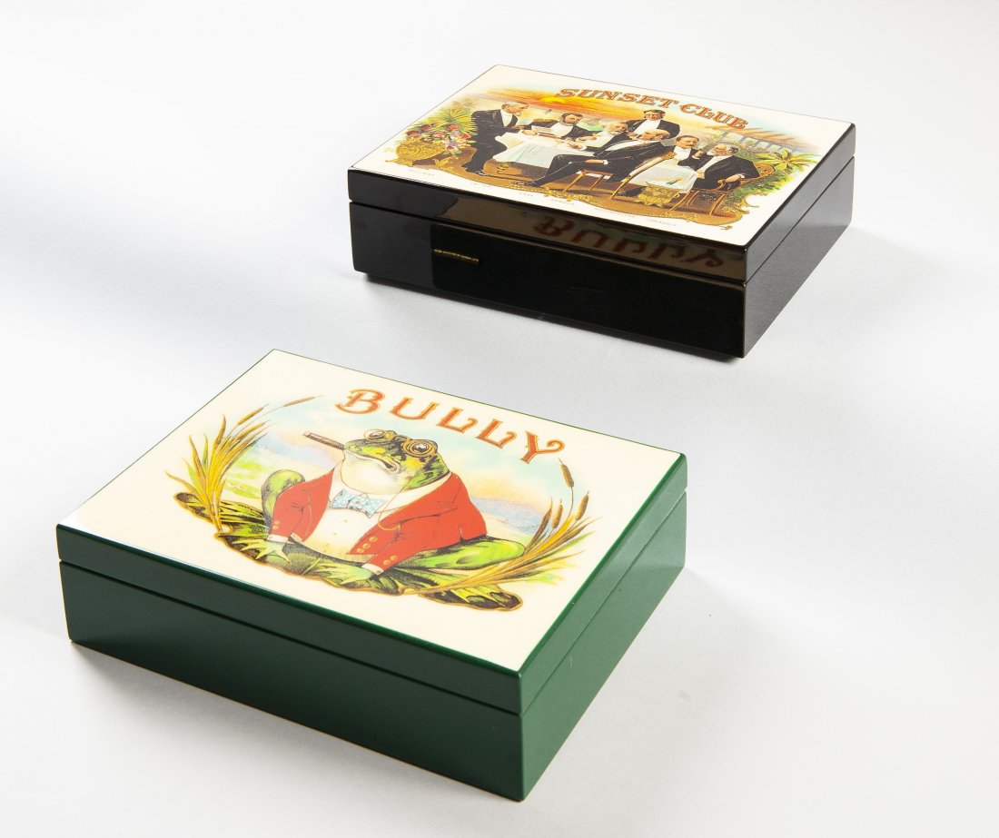 2 Wood Cigar Box Humidors: DESCRIPTION: Two lacquered wood cigar box humidors. Includes: 1) Green box with brass hinges. Lid titled "BULLY" with graphic of a frog. 2) Black box with brass hinges. Lid titled "Sunset Club", depic