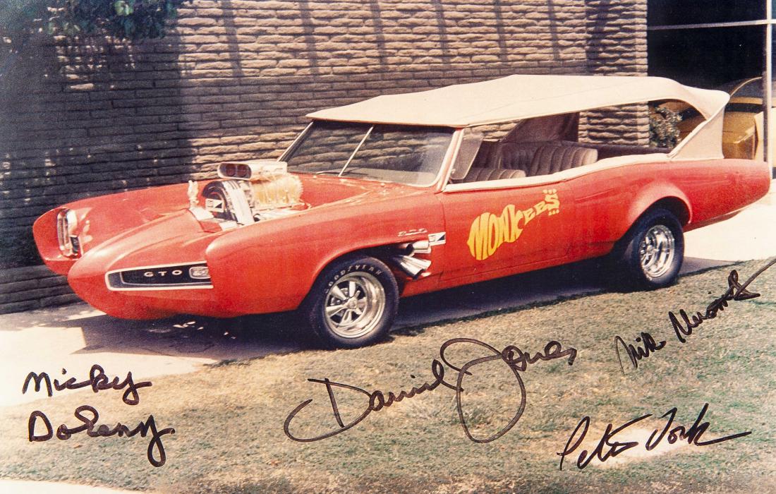 The Monkees Signed Photo: DESCRIPTION: Color photograph of the "Monkeemobile" autographed by all four members of The Monkees in black marker. Signatures include Micky Dolenz, David Jones, Peter Tork, and Michael Nesmith. MEASU